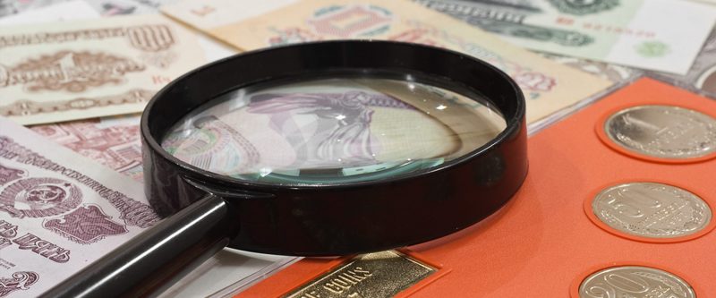 Coins, Paper Money and Magnifying Glass